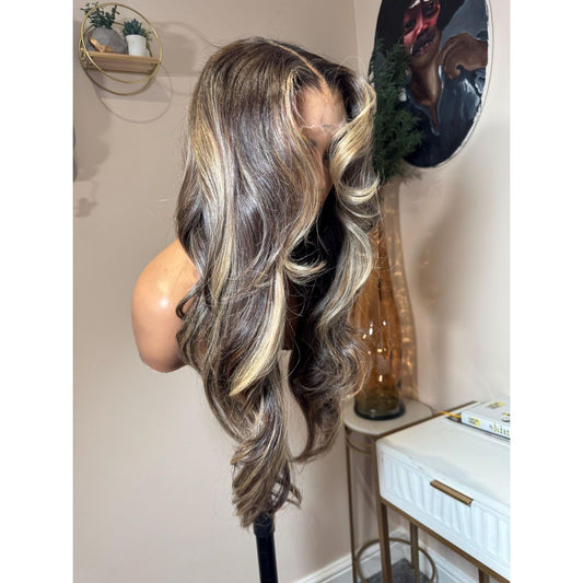 Mannequin head with long, wavy blonde highlights hair styled in a room setting.