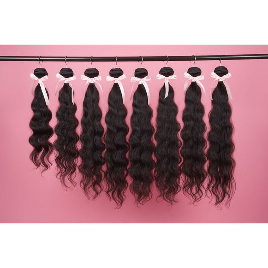 Set of black wavy hair extensions on a pink background