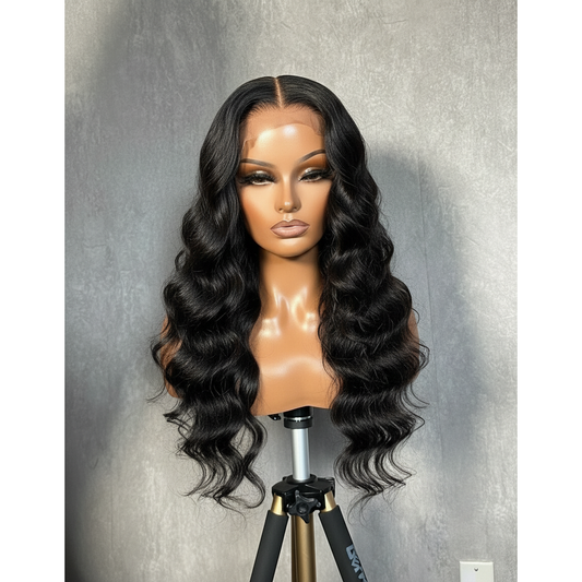 Black wig on a mannequin head against a gray background