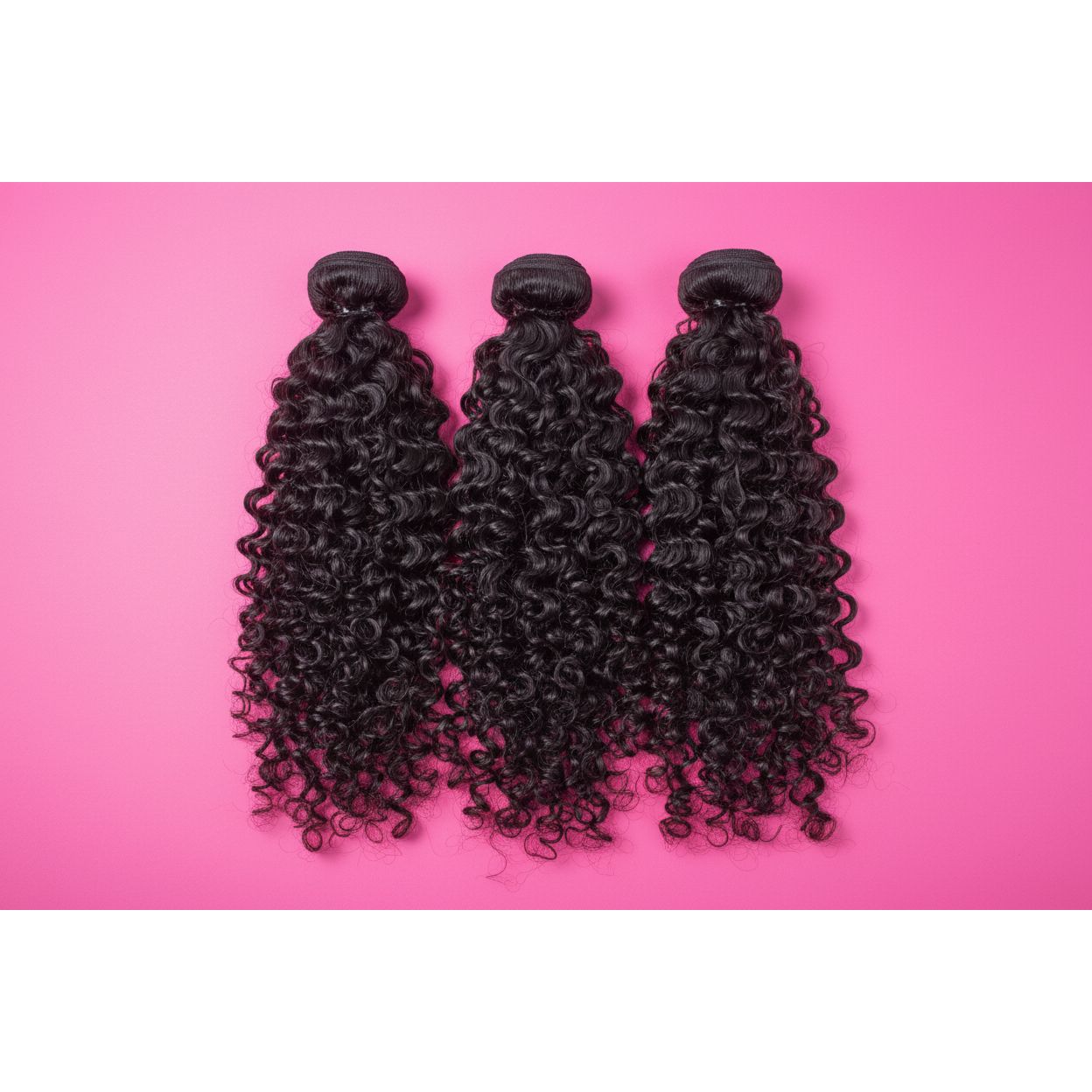 Three bundles of curly hair extensions on a pink background